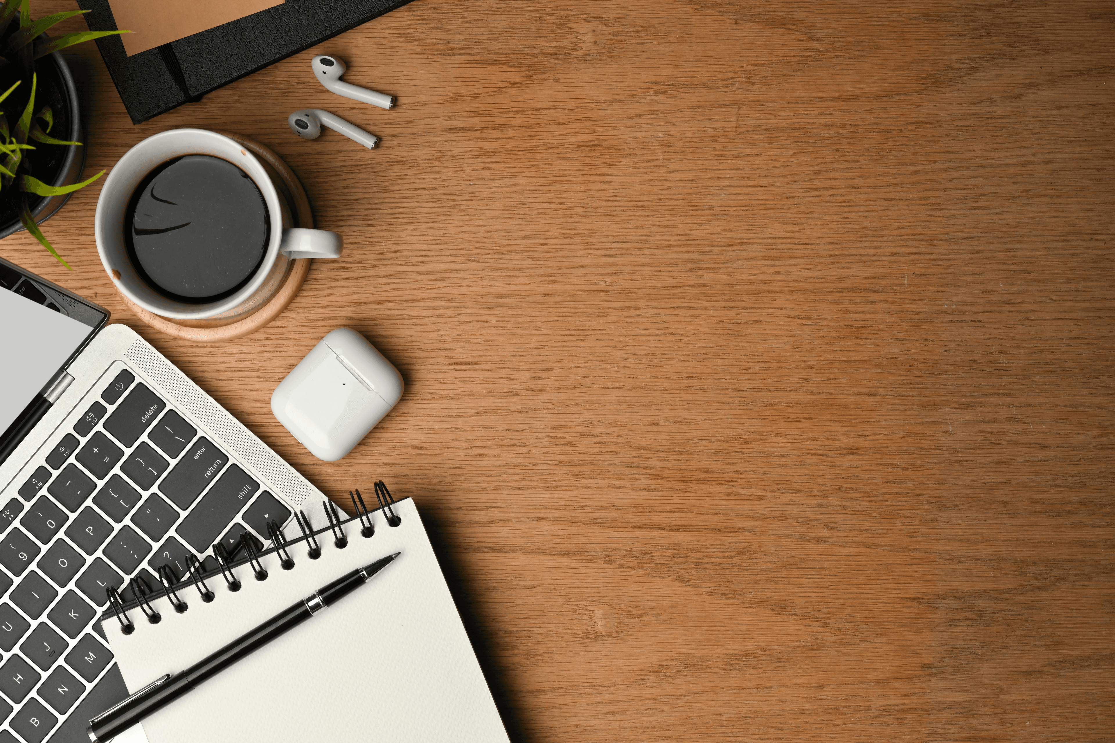 Coffee, earbuds, Macbook and pencil and notepad on wooden desk